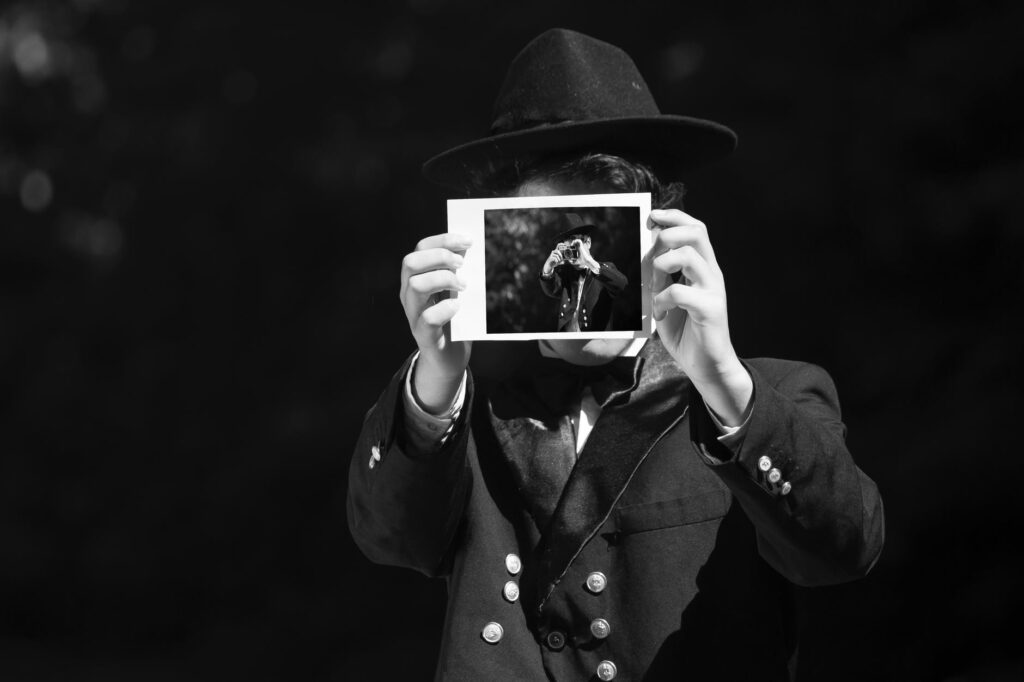 grayscale photo of person wearing hat and coat holding photo