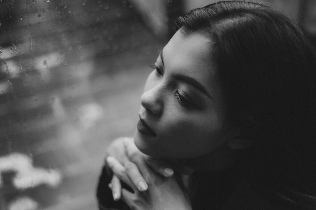 dreamy teen girl sitting near wet window