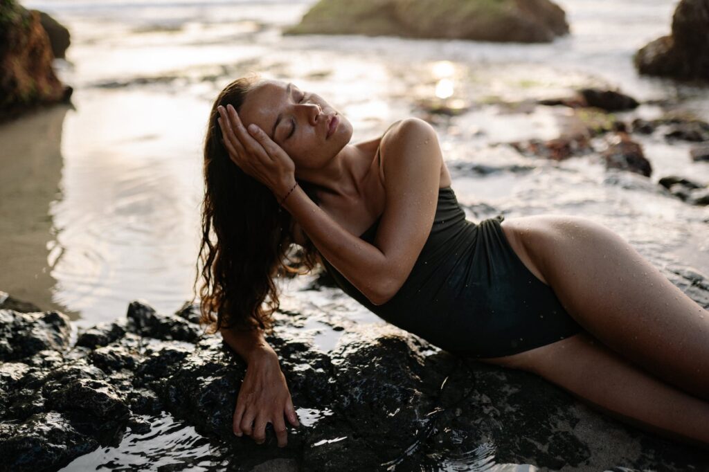 sensual lady in bathing suit relaxing on rocky seashore