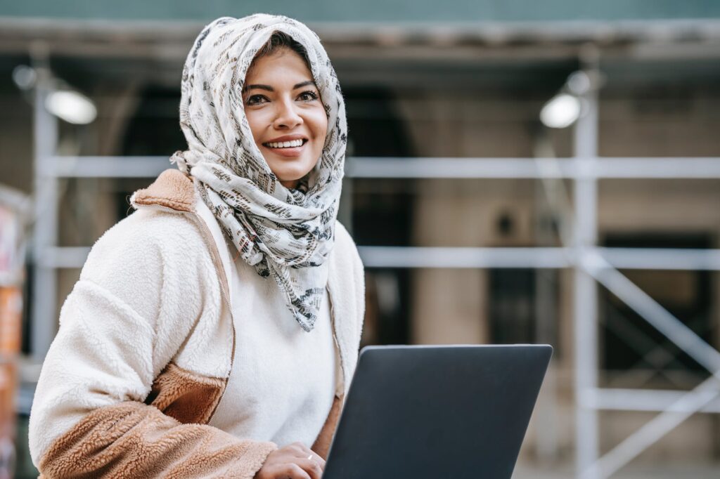 content young muslim woman working on laptop on street