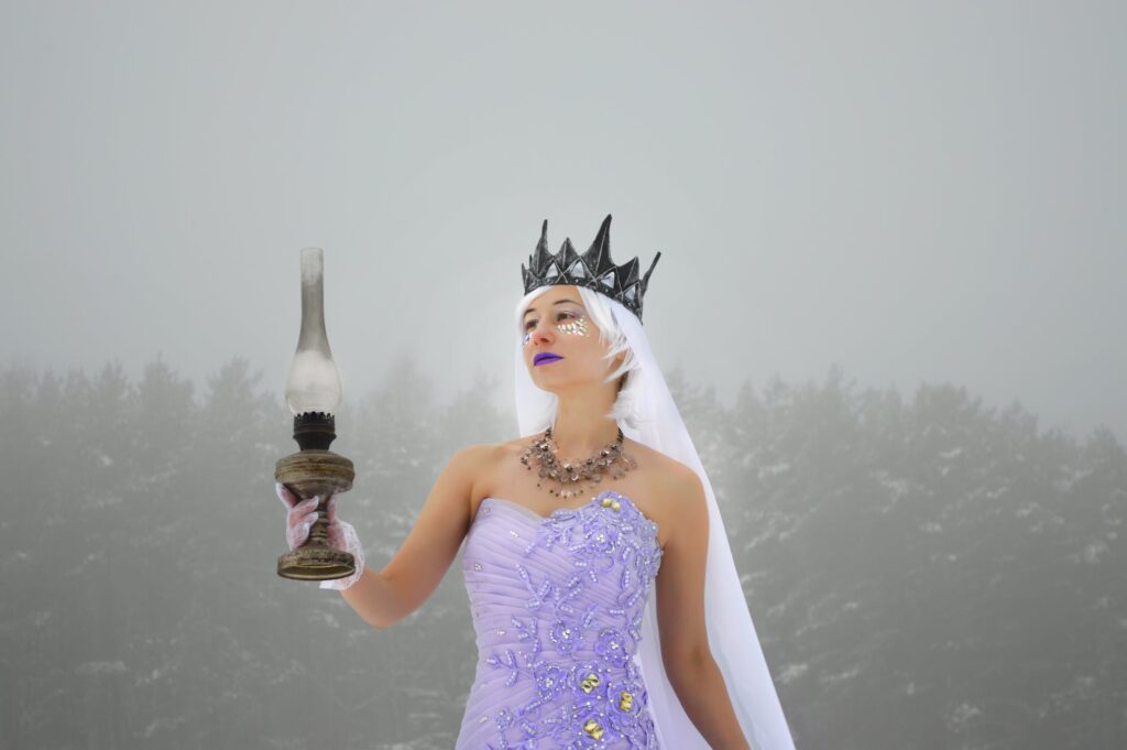 female in crown and dress holding kerosene lamp in winter