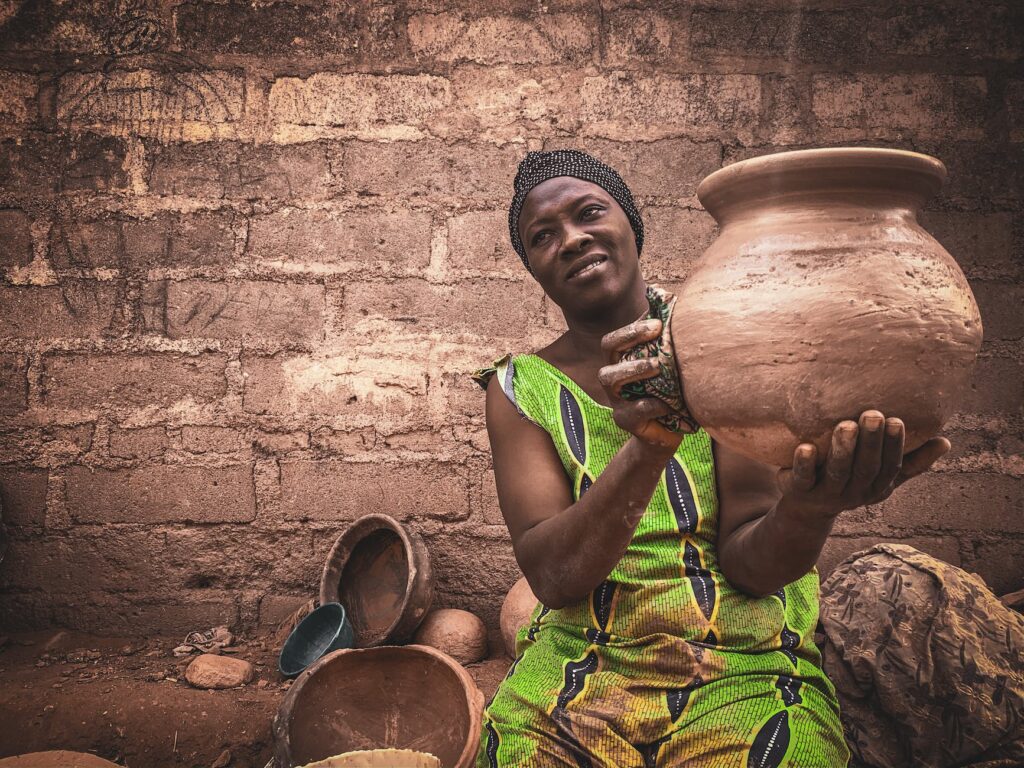 african woman showing handicraft earthenware in local workshop